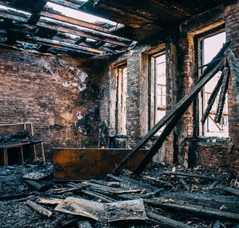 Burnt room interior with walls, furniture and floor in ash and coal, ruined building after fire, toned